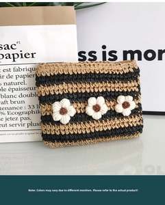 Detail of handwoven crochet envelope bag with striped pattern and white floral accents