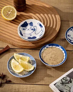 Detail of Japanese ceramic cat sauce dish on wooden tray with fresh lemon and spices