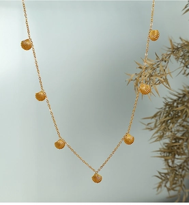 Detail of gold necklace featuring seven delicate scallop shell pendants on a fine chain