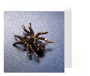 Detailed view of a vintage spider brooch with purple crystals and opal on a textured fabric
