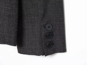 Detail of dark grey suit sleeve featuring three black buttons and premium fabric texture