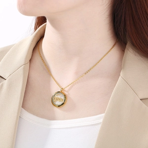 Détail d'un collier doré 18K avec pendentif rond orné de perles et texte Love