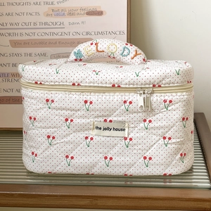 Close-up of quilted cherry print makeup bag with embroidered Melody handle and dual zippers