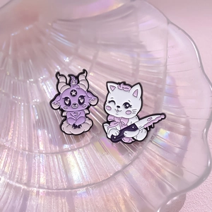 Detail of gothic purple goat and dark cat enamel pins on iridescent shell tray