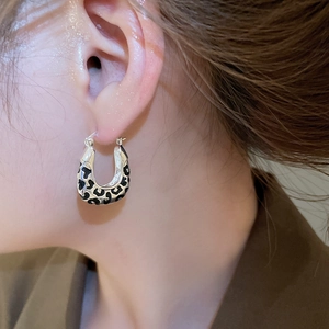 Close-up of vintage leopard print square drop earrings worn by a model in soft lighting
