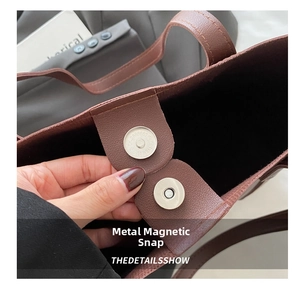 Close-up of the magnetic buckle closure on a brown pebble leather tote bag for women