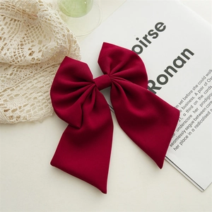 Close-up of elegant burgundy oversized bow hair clip made of premium plain fabric