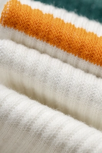 Macro view of breathable combed cotton yoga socks with orange and white knit stripes