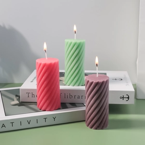 Spiral cylindrical scented candle mold in pink, green and purple on minimalist books