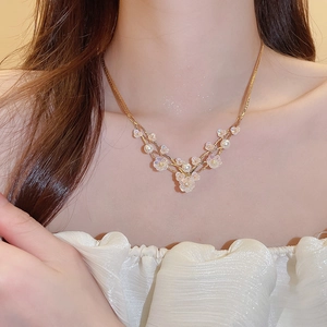 Detail of floral pearl pendant necklace with gold chain on model neck
