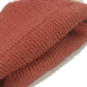 Close-up of rust red knit beanie showing soft plush faux fur texture and ribbed pattern