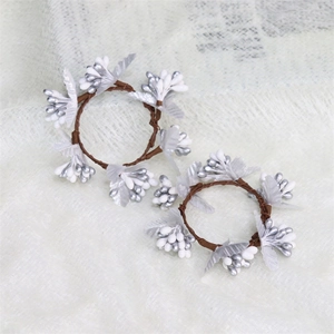 Silver and white berry Christmas napkin rings on brown rattan for holiday table decor