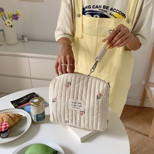 Close-up of beige quilted diaper bag with floral embroidery and adjustable strap