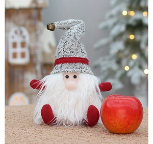 Close-up of a Christmas gnome plush decoration with a red apple and festive background