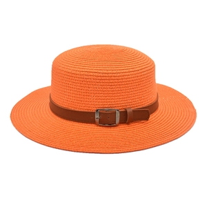 Detalle de sombrero de paja naranja con banda de cuero marrón y hebilla metálica plateada