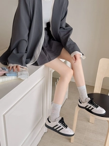 Detail shot of light grey ribbed crew socks paired with classic vintage leather sneakers
