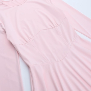 Détail d'une robe rose à manches longues montrant la découpe à la taille et le tissu