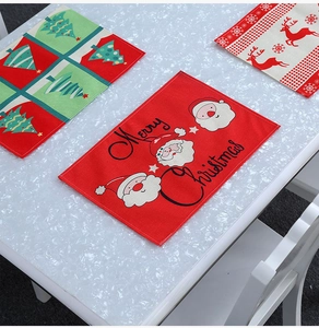 Set of three Christmas placemats with Santa, reindeer, and tree patterns on white table