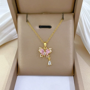 Dettaglio di un ciondolo a farfalla con zircone rosa e goccia d'acqua su catena d'oro