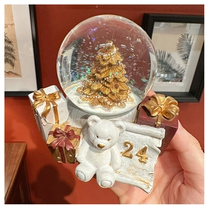 Detail of hand-held vintage Christmas snow globe featuring gold tree and resin base