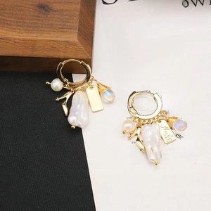 Detail shot of vintage gold earrings with baroque pearl and high heel charms on paper