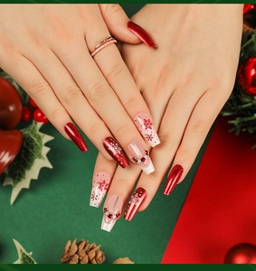 Close-up of long coffin press-on nails with Christmas snowflake art and red rhinestones
