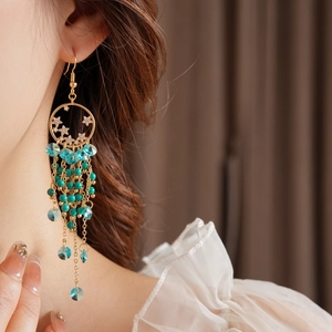 Gros plan de boucles d'oreilles vintage dorées avec perles turquoise et pompons
