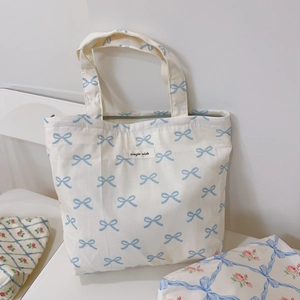 Detail of white canvas tote with blue bow pattern and simple wish label text