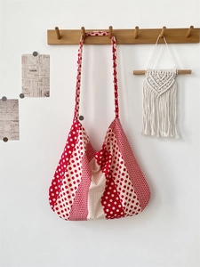 Detail of red and white polka dot canvas tote bag hanging on a minimalist wooden rack