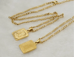 Détail du collier chaîne Figaro en or 18K avec pendentif carré et gravure de la lettre A