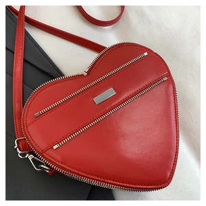 Close-up of a red heart-shaped shoulder bag featuring silver metal zipper and stitching