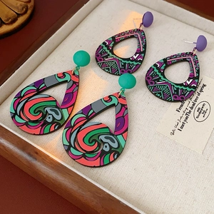Détail de boucles d'oreilles bohèmes en forme de goutte avec motifs colorés sur plateau