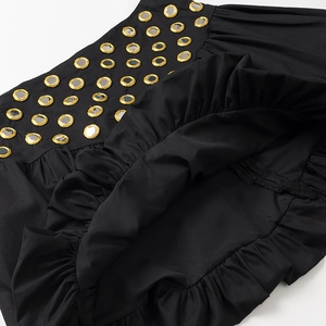 Détail du tissu noir avec cadres brodés dorés et accents de miroir métallique sur la robe