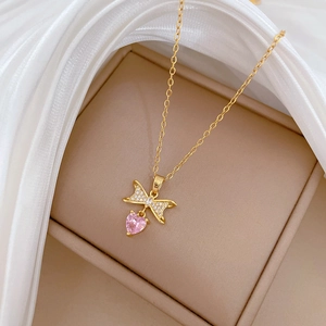 Close-up of golden bow necklace with pink heart gemstone on elegant silk fabric