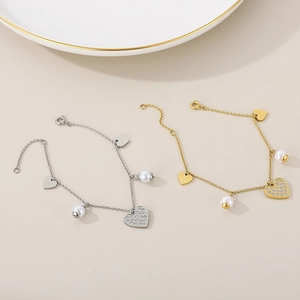 Detailed view of silver and gold heart pendants with white pearls on dainty link bracelets