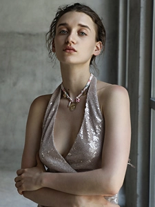 Detail of 18K gold sun pendant on colorful braided rope necklace worn by a model