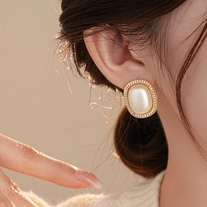 Close-up of vintage golden oval earrings with a large center pearl and zircon halo