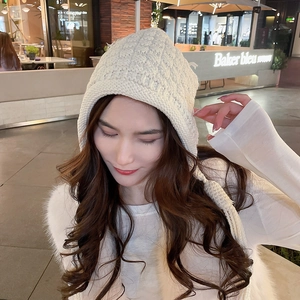 Detail of chunky knit cream beanie showing handmade crochet texture and braided tassels