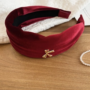 Detail showing the soft red velvet texture and golden bow ornament on the headband