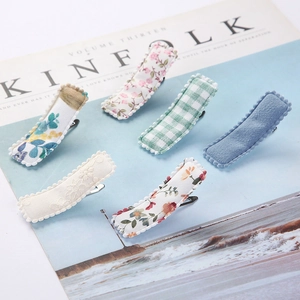 Detailed flat lay of 6-piece floral embroidery fabric hair clips on a magazine background