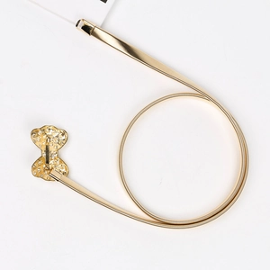 Détail d'une ceinture dorée élastique à ressort avec boucle de nœud en strass brillant