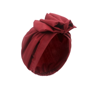 Macro detail of burgundy turban hat featuring elegant flower pleats and elastic hem