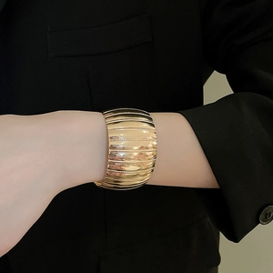 Detailed view of a wide gold textured metal cuff bracelet with horizontal striped patterns