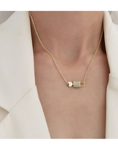 Detail der goldene Halskette mit diamantbesetztem Schloss-Anhänger an weißem Blazer