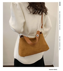 Détail d'un sac porté épaule en daim marron avec fermoir argenté sur un mannequin
