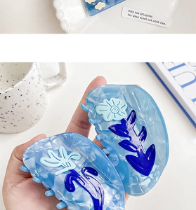Close-up of blue floral cellulose acetate hair claw clip with elegant marble texture