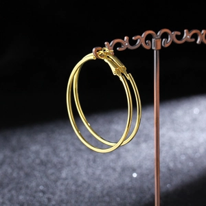 Detailed side view of large gold hoop earrings on a vintage bronze display stand