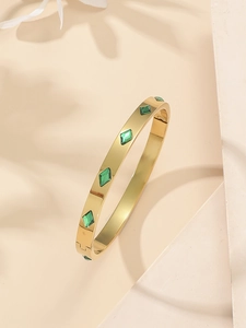 Detail of gold titanium steel bangle with embedded green rhombus diamonds and clasp