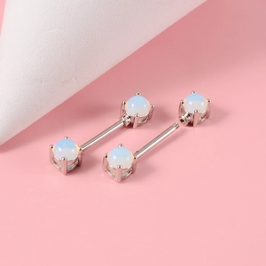 Detailed macro view of opal nipple piercings with silver steel bars and screw threads