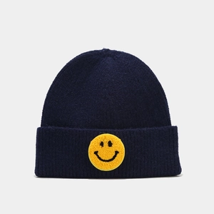 Détail du bonnet en tricot bleu marine montrant le patch smiley jaune texturé